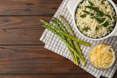Delicious risotto with asparagus served on wooden table, flat lay. Space for text