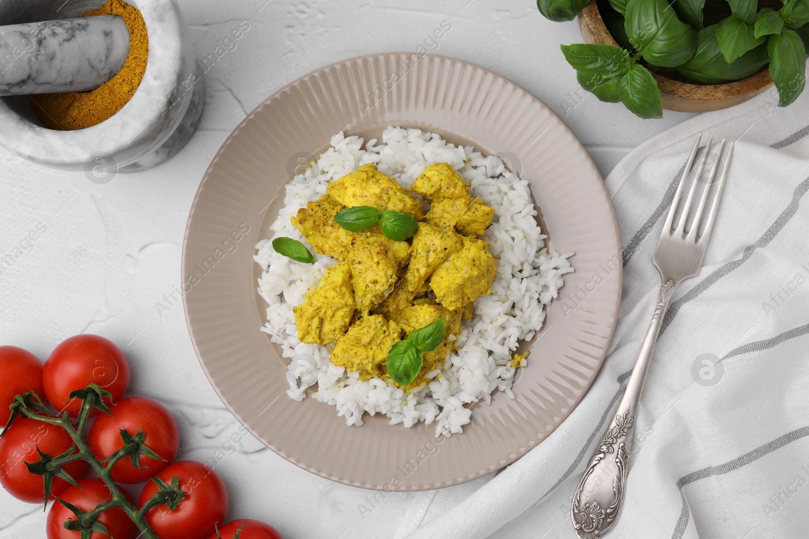 Photo of Delicious rice, chicken with curry sauce and products on white textured table, flat lay