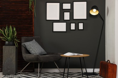 Photo of Empty frames hanging on black wall in stylish room. Mockup for design