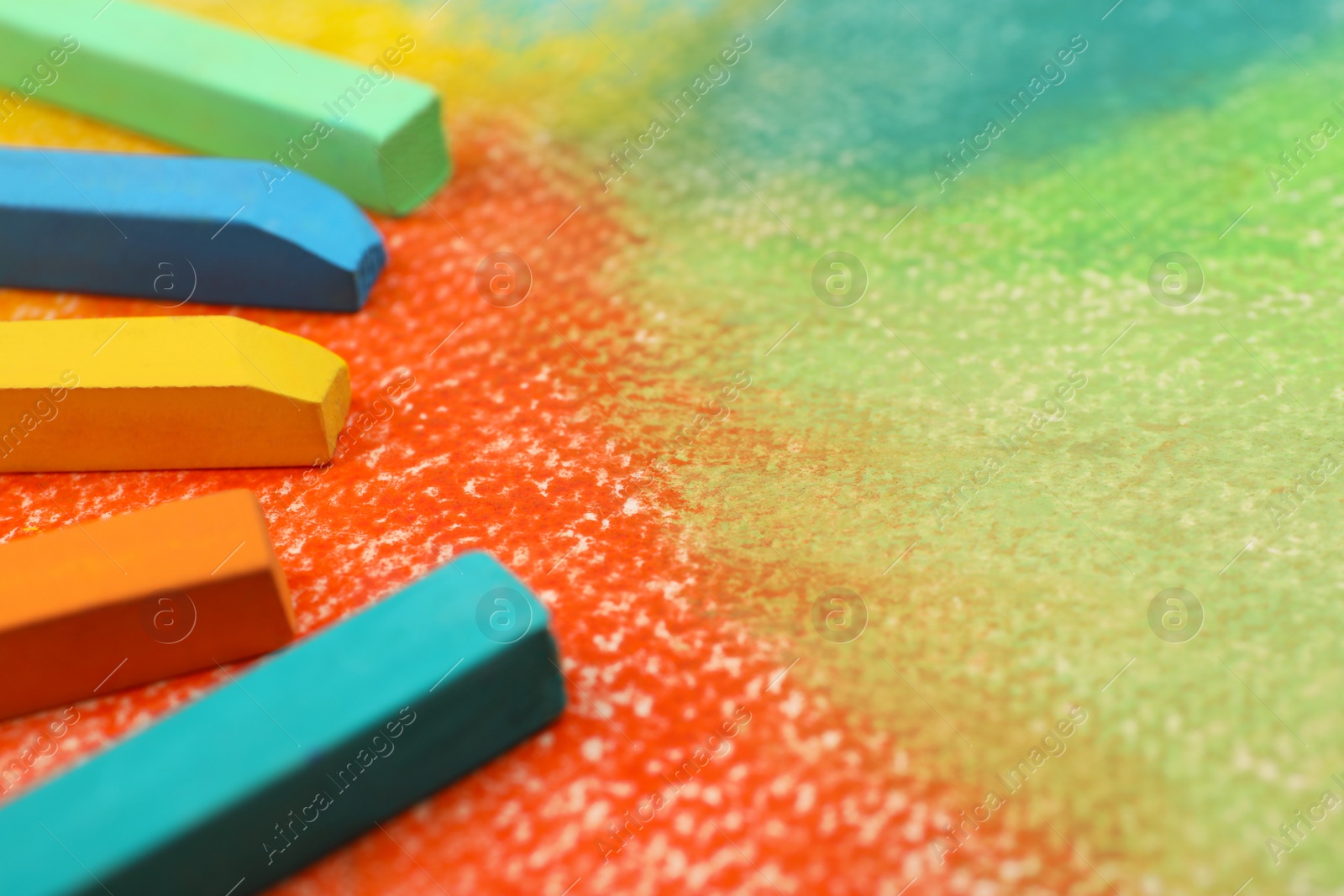 Photo of Colorful pastel chalks on abstract drawing, closeup. Space for text