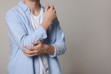 Photo of Man suffering from pain in his elbow on light grey background, closeup with space for text. Arthritis symptoms