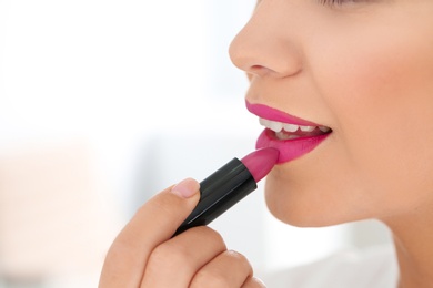 Photo of Beautiful woman applying lipstick on light background, closeup