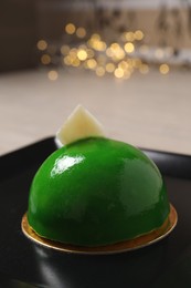 Photo of Delicious dessert decorated with white chocolate on plate against blurred lights, closeup