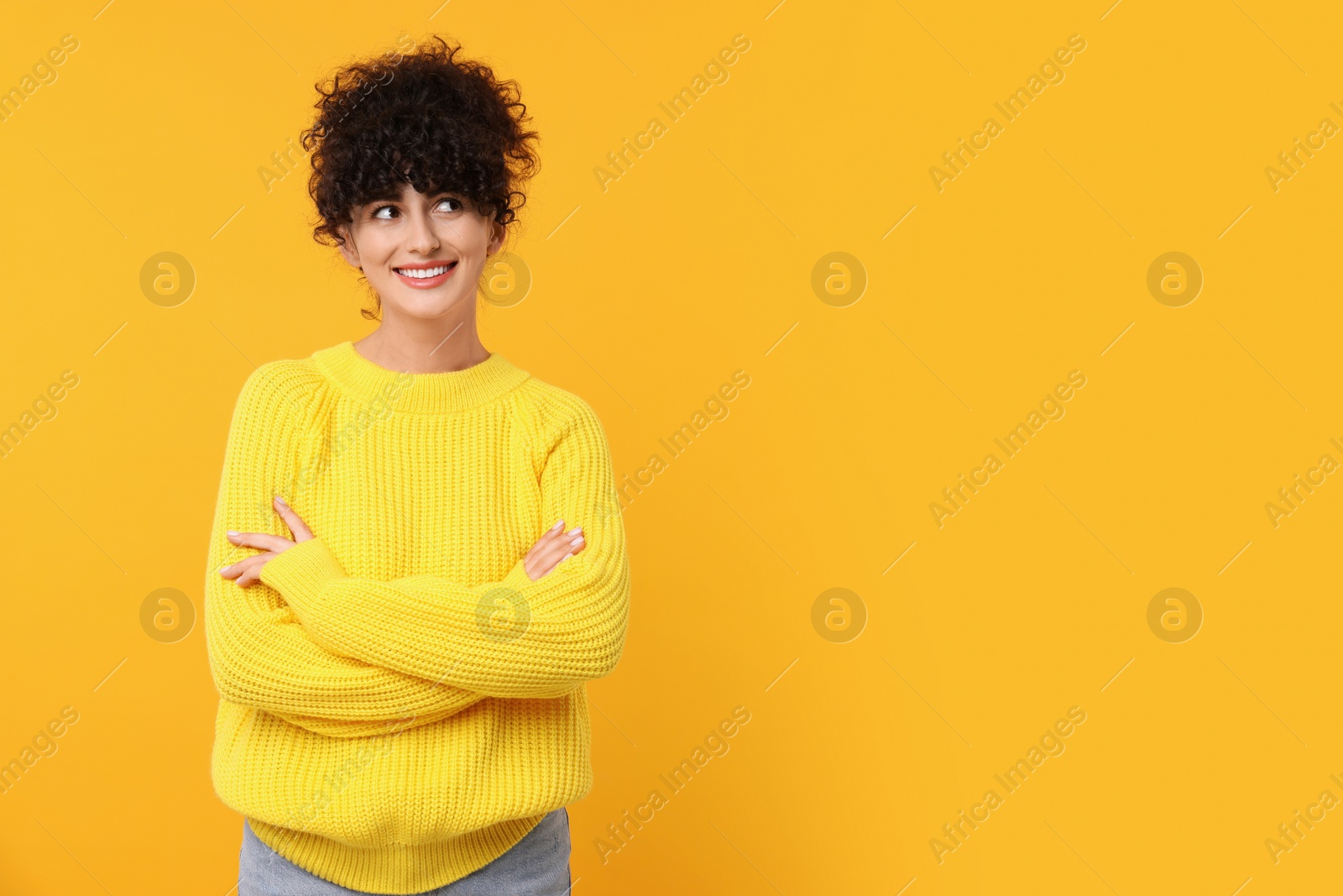 Photo of Happy young woman in stylish warm sweater on yellow background, space for text