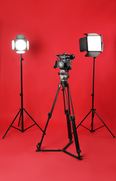 Professional video camera and lighting equipment on red background