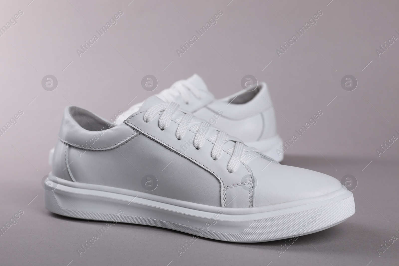 Photo of Pair of stylish white sneakers on grey background