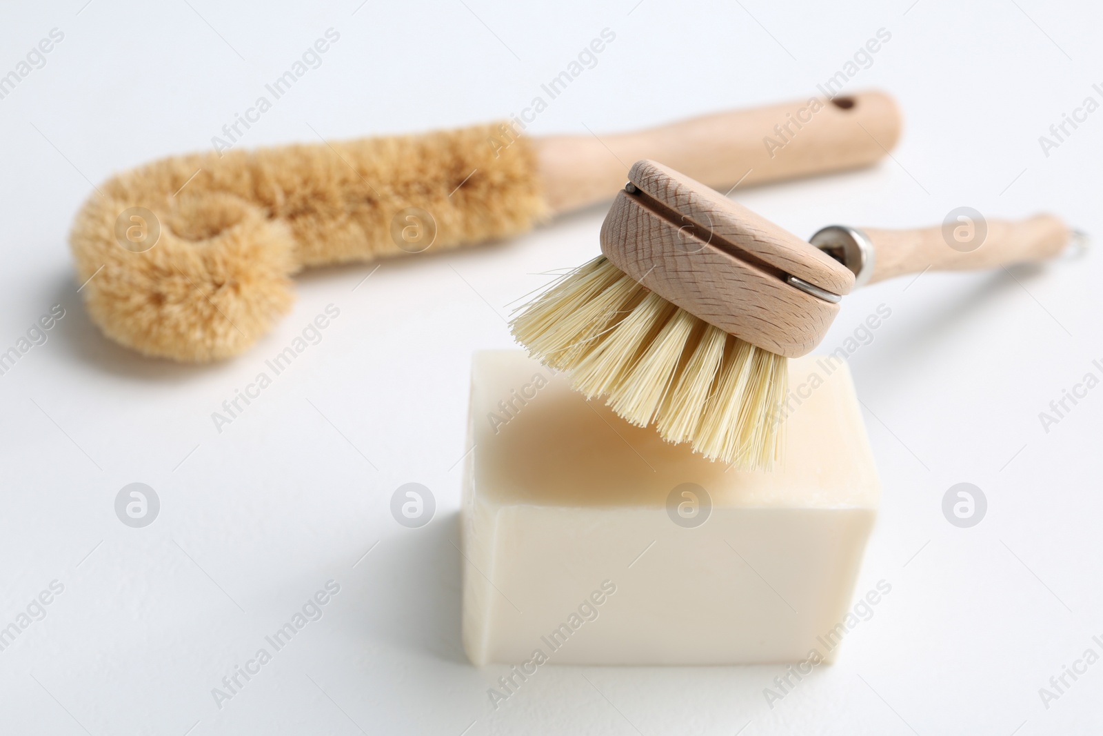 Photo of Cleaning brushes and soap bar for dish washing on white background, closeup