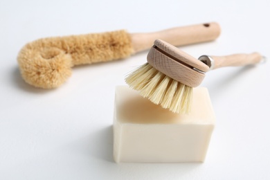 Photo of Cleaning brushes and soap bar for dish washing on white background, closeup