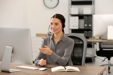 Hotline operator with headset working on computer in office