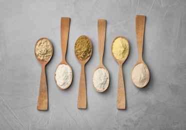 Photo of Spoons with different types of flour on gray background