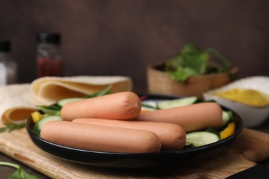 Delicious breakfast with boiled sausages on wooden table, closeup