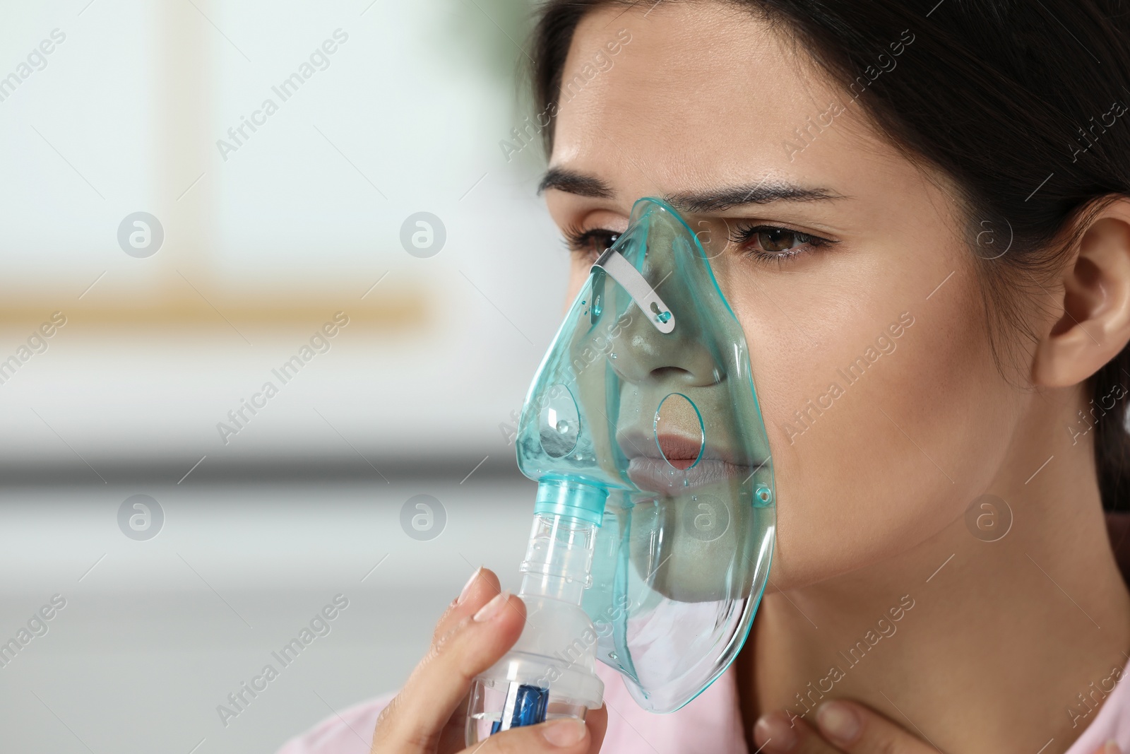 Photo of Sick young woman using nebulizer at home, closeup. Space for text