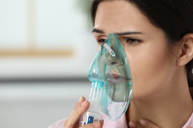 Sick young woman using nebulizer at home, closeup. Space for text