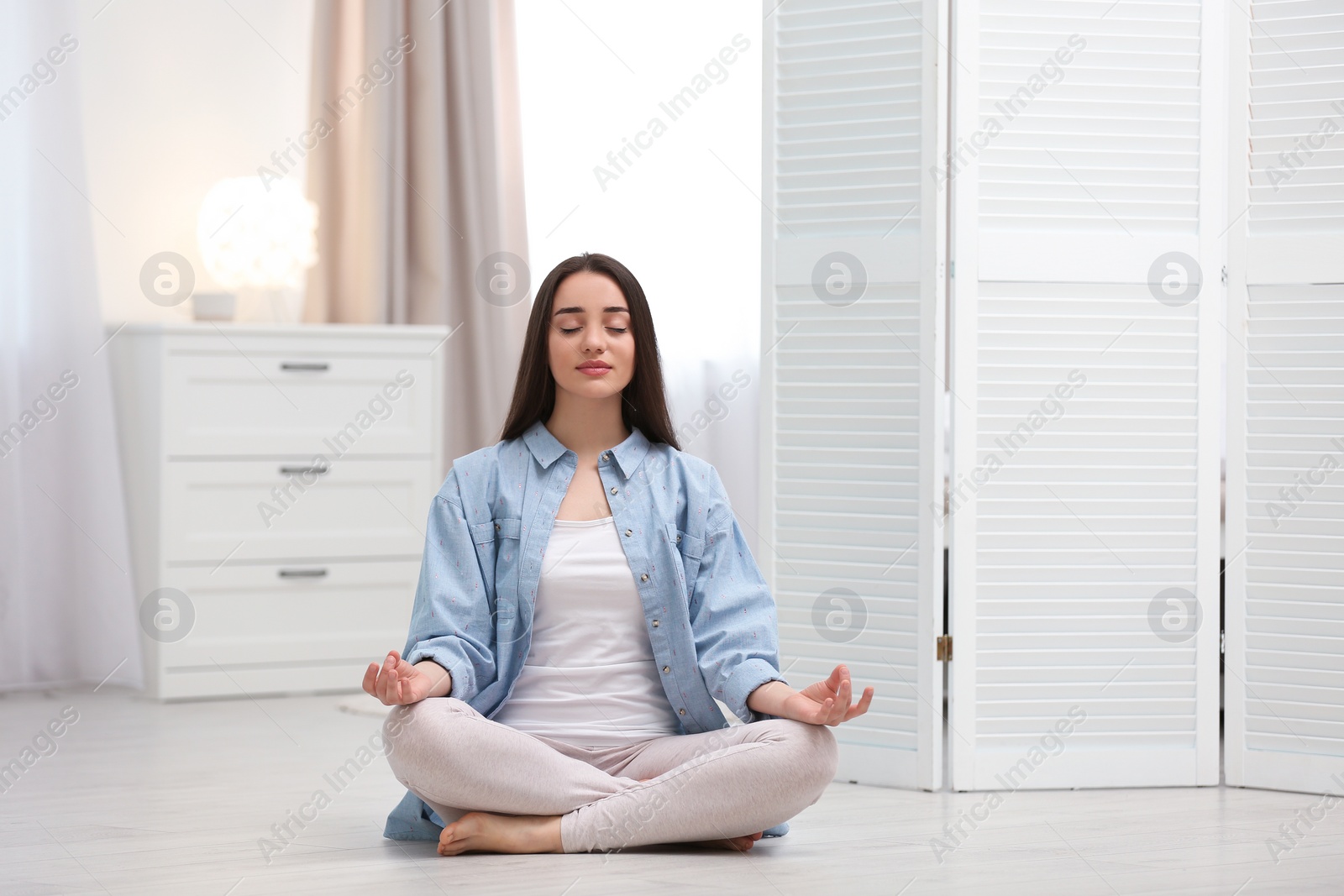 Photo of Young woman meditating on floor at home. Zen concept