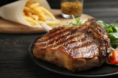 Photo of Tasty grilled beef steak on black wooden table, closeup