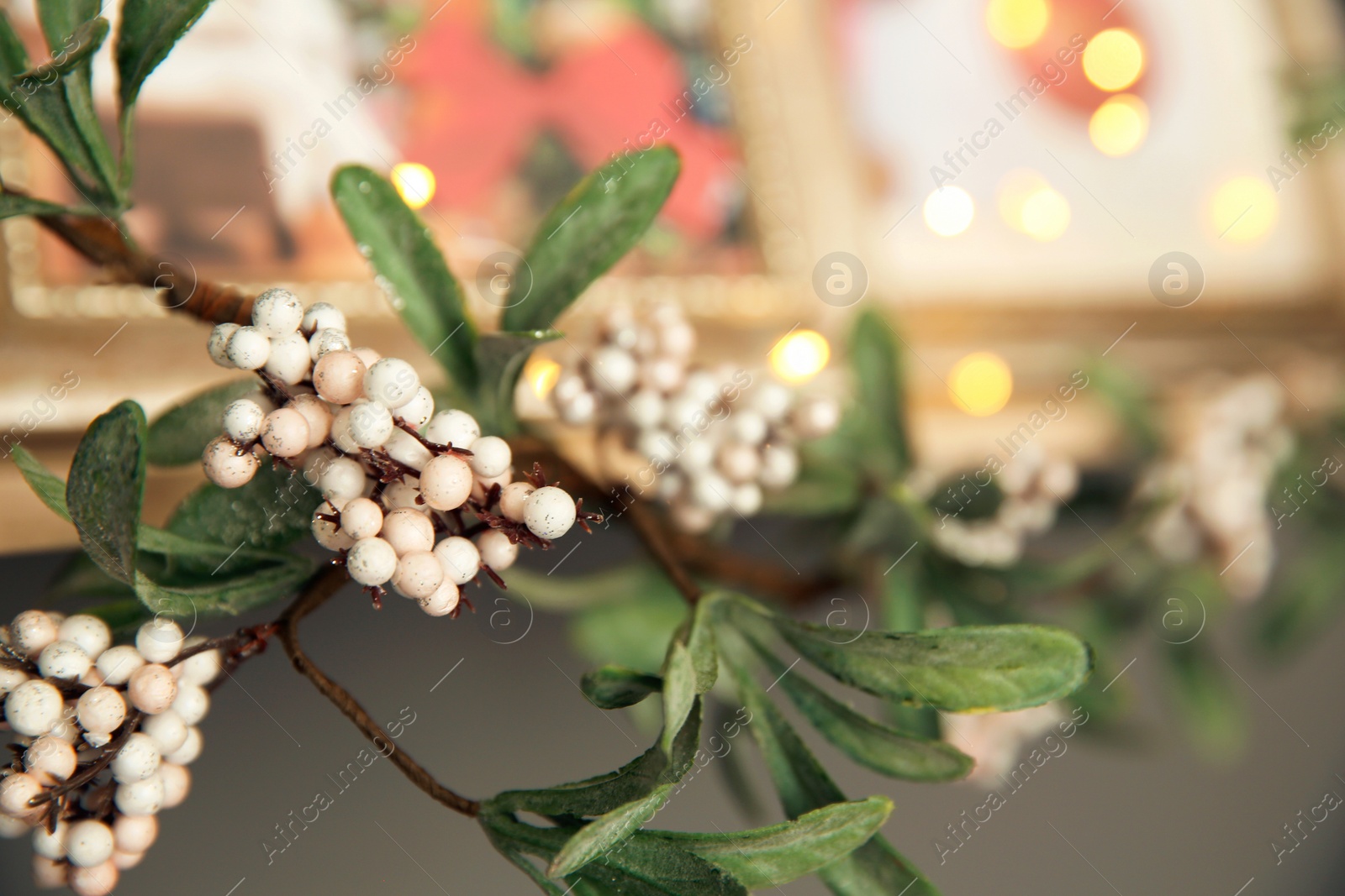 Photo of Christmas decoration made of mistletoe with berries on shelf, closeup