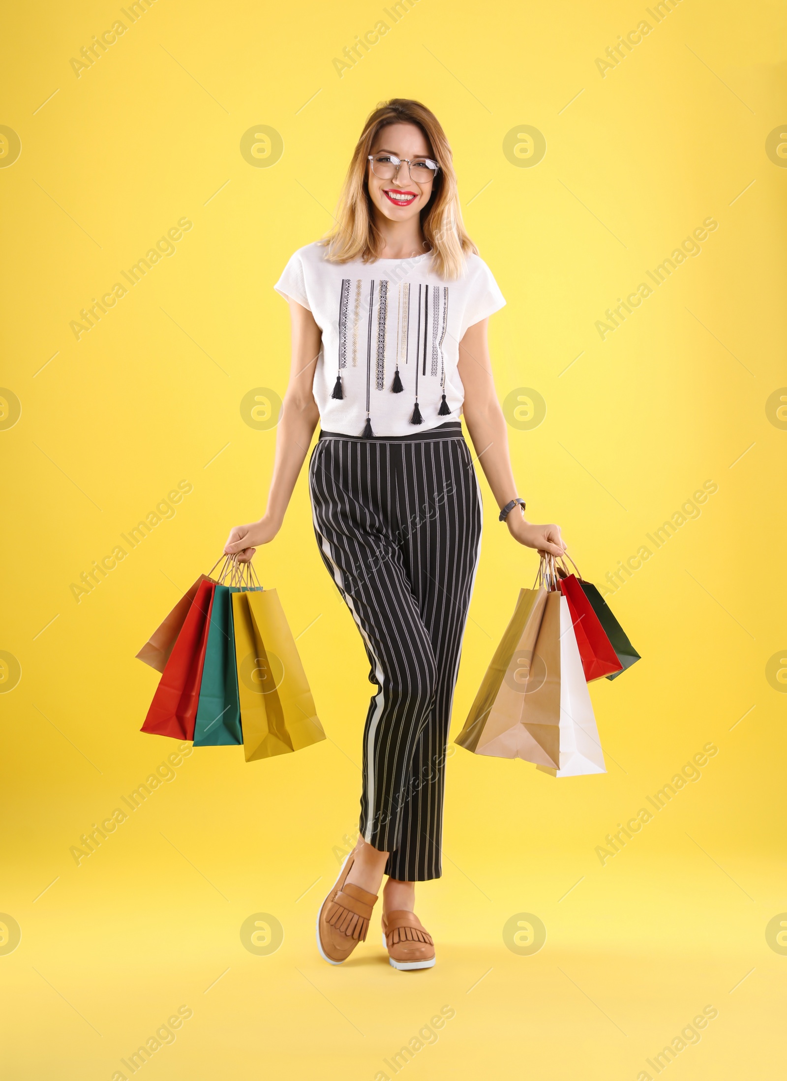 Photo of Beautiful young woman with shopping bags on color background