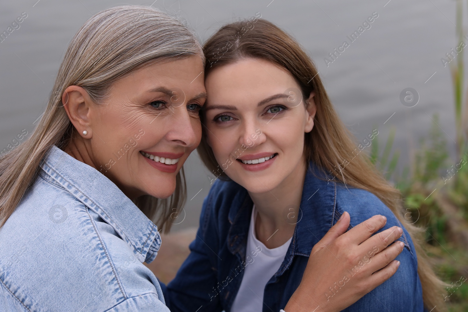 Photo of Happy mature mother and her daughter near pond