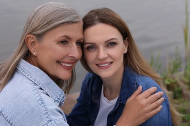 Happy mature mother and her daughter near pond