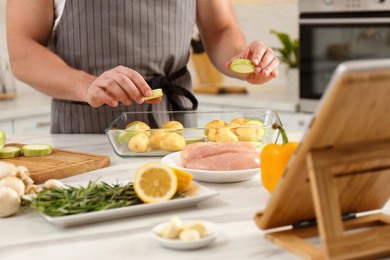 Man making dinner while watching online cooking course via tablet in kitchen, closeup