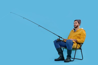 Photo of Fisherman with rod on fishing chair against light blue background