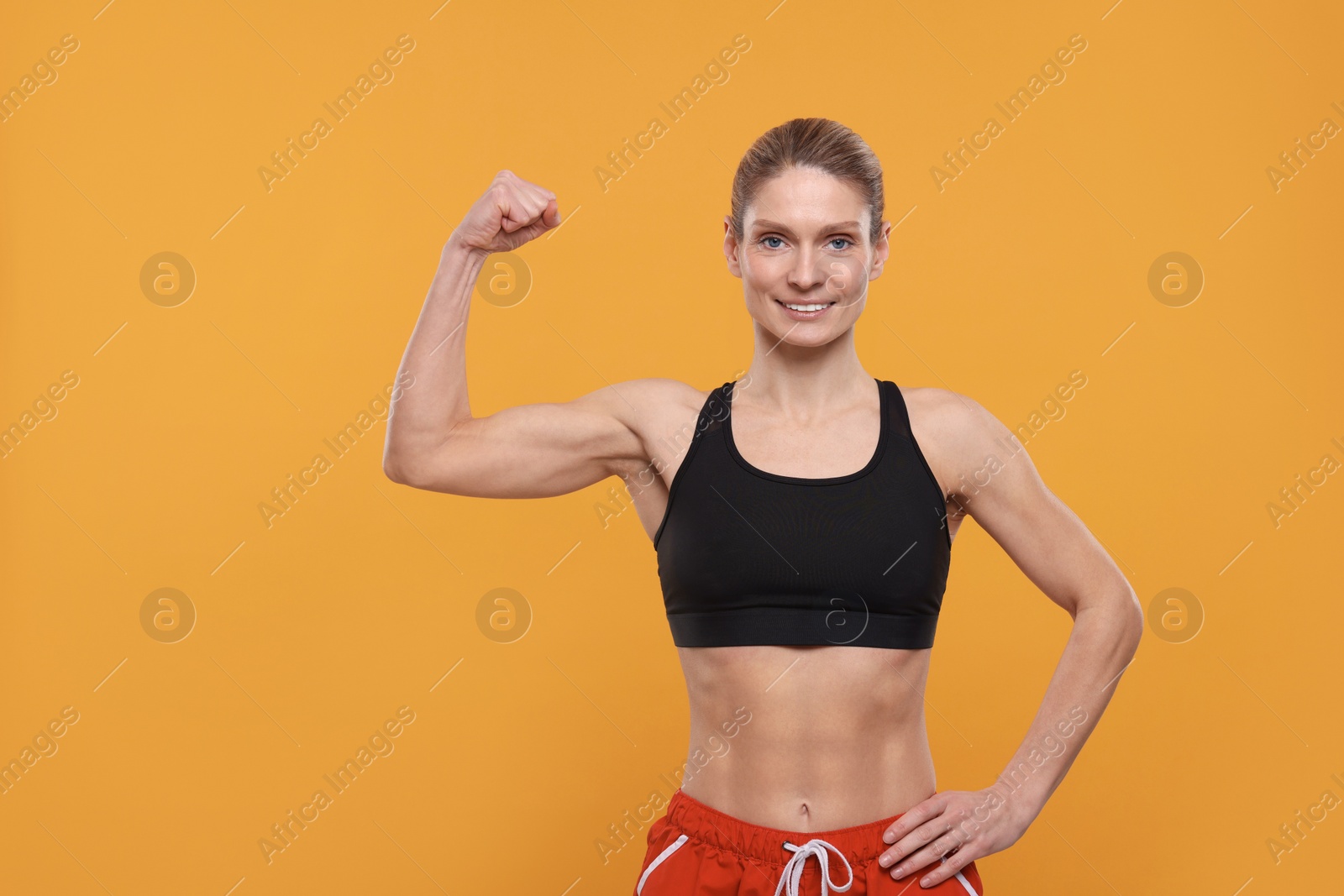 Photo of Portrait of sportswoman showing muscles on yellow background, space for text
