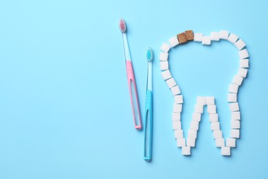 Photo of Composition with tooth outline made of sugar cubes near toothbrushes, flat lay. Caries problem