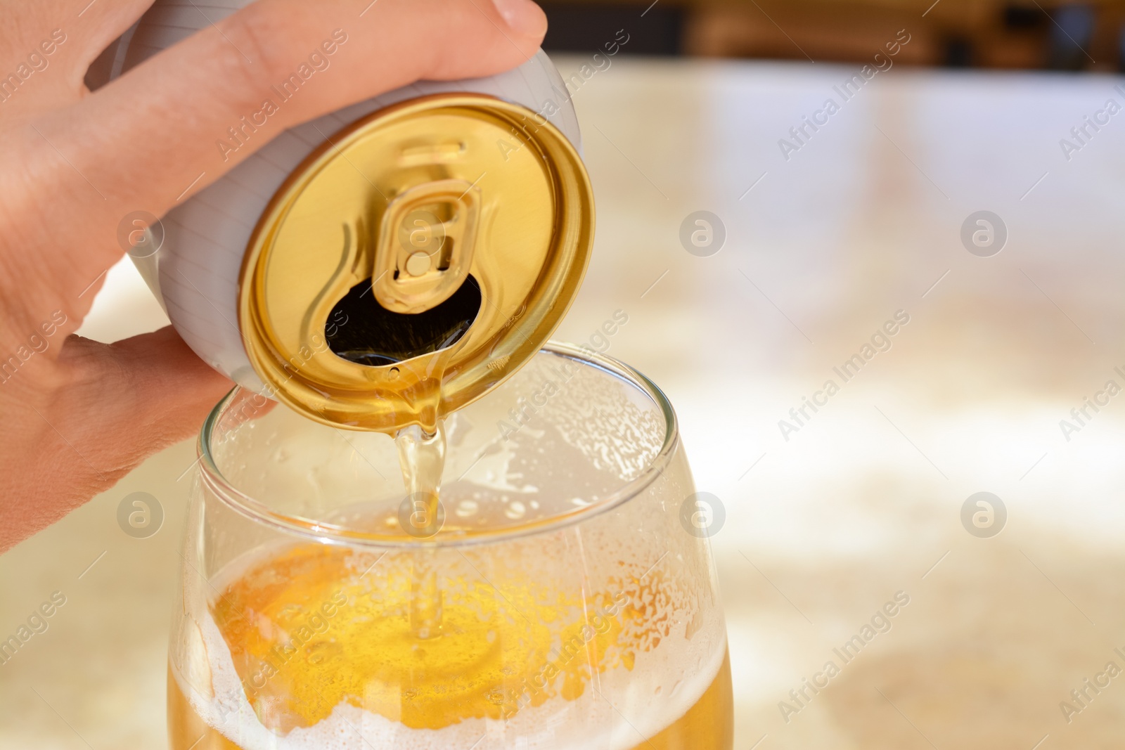 Photo of Man pouring beer from can into glass at table, closeup. Space for text