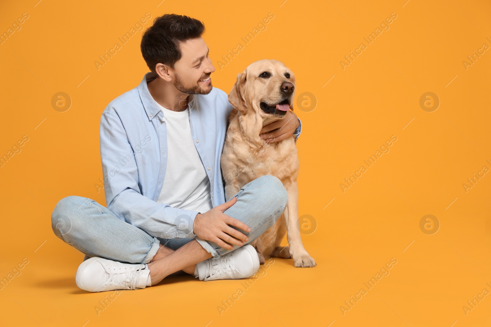 Photo of Happy man with his cute Labrador Retriever on yellow background. Space for text