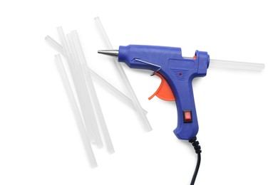 Blue glue gun and sticks on white background, top view