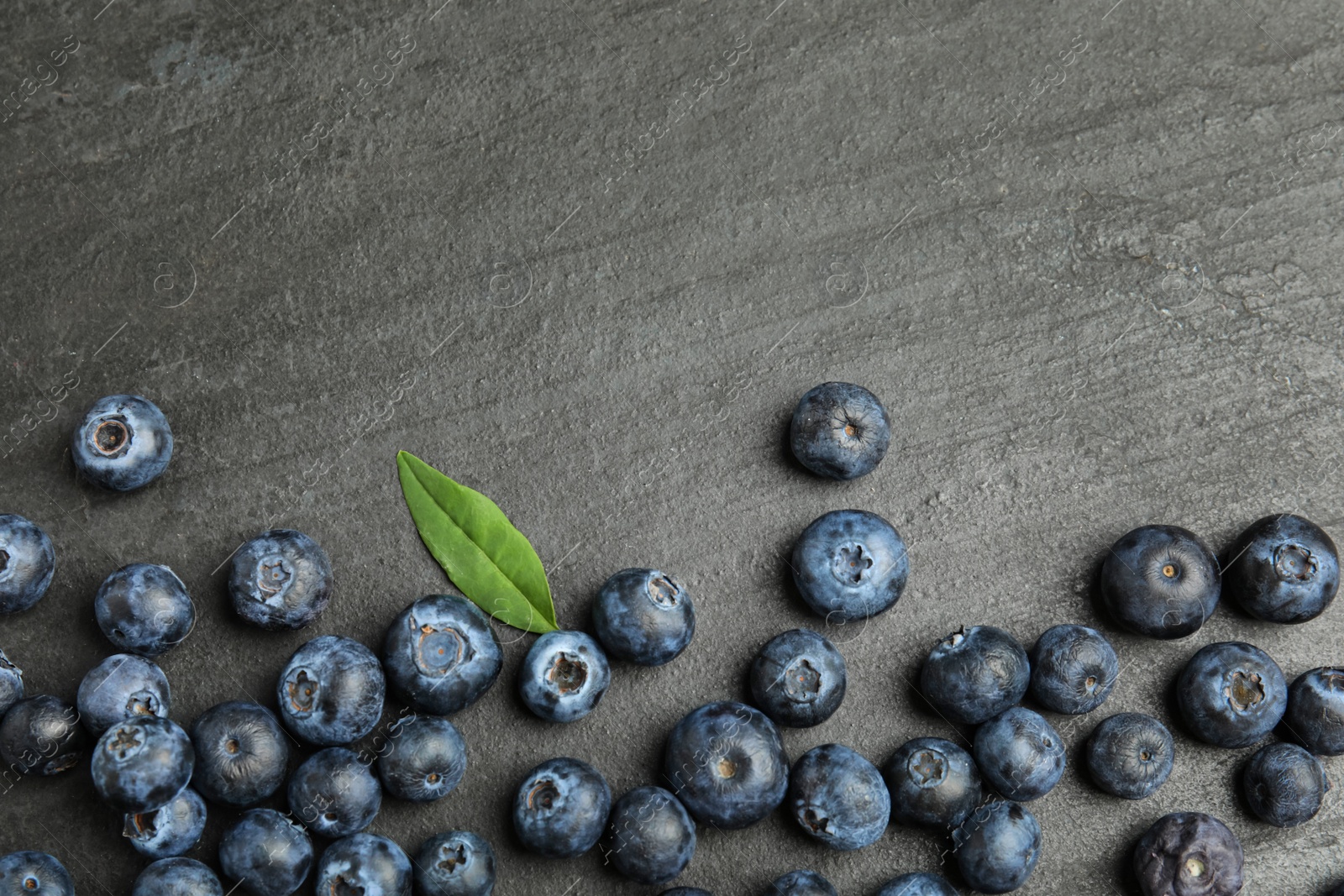 Photo of Fresh ripe blueberries on dark grey table, flat lay. Space for text