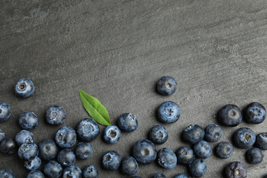 Photo of Fresh ripe blueberries on dark grey table, flat lay. Space for text