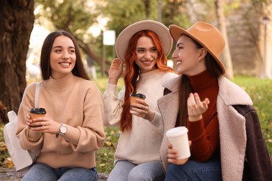 Photo of Happy friends talking and enjoying coffee in park