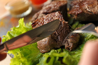 Woman eating tasty shish kebab in cafe