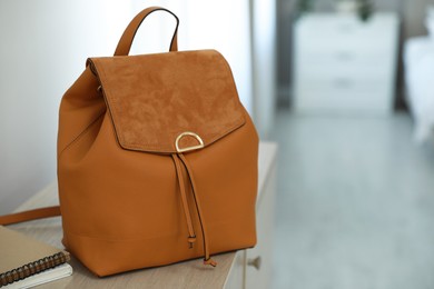 Stylish brown backpack and notebooks on wooden table indoors, space for text