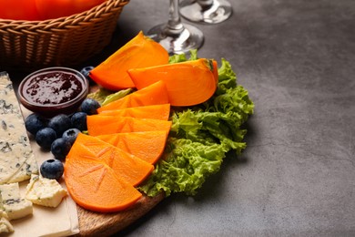 Delicious persimmon, blue cheese, blueberries and jam served on light grey table. Space for text