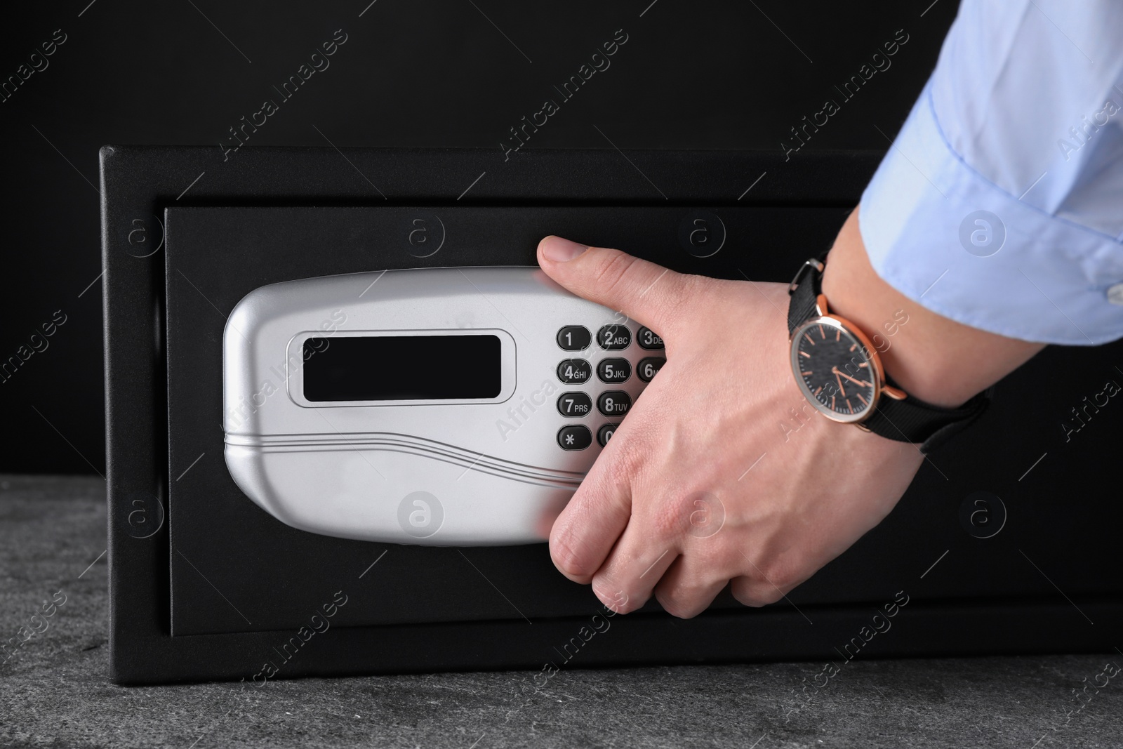 Photo of Man opening black steel safe with electronic lock, closeup