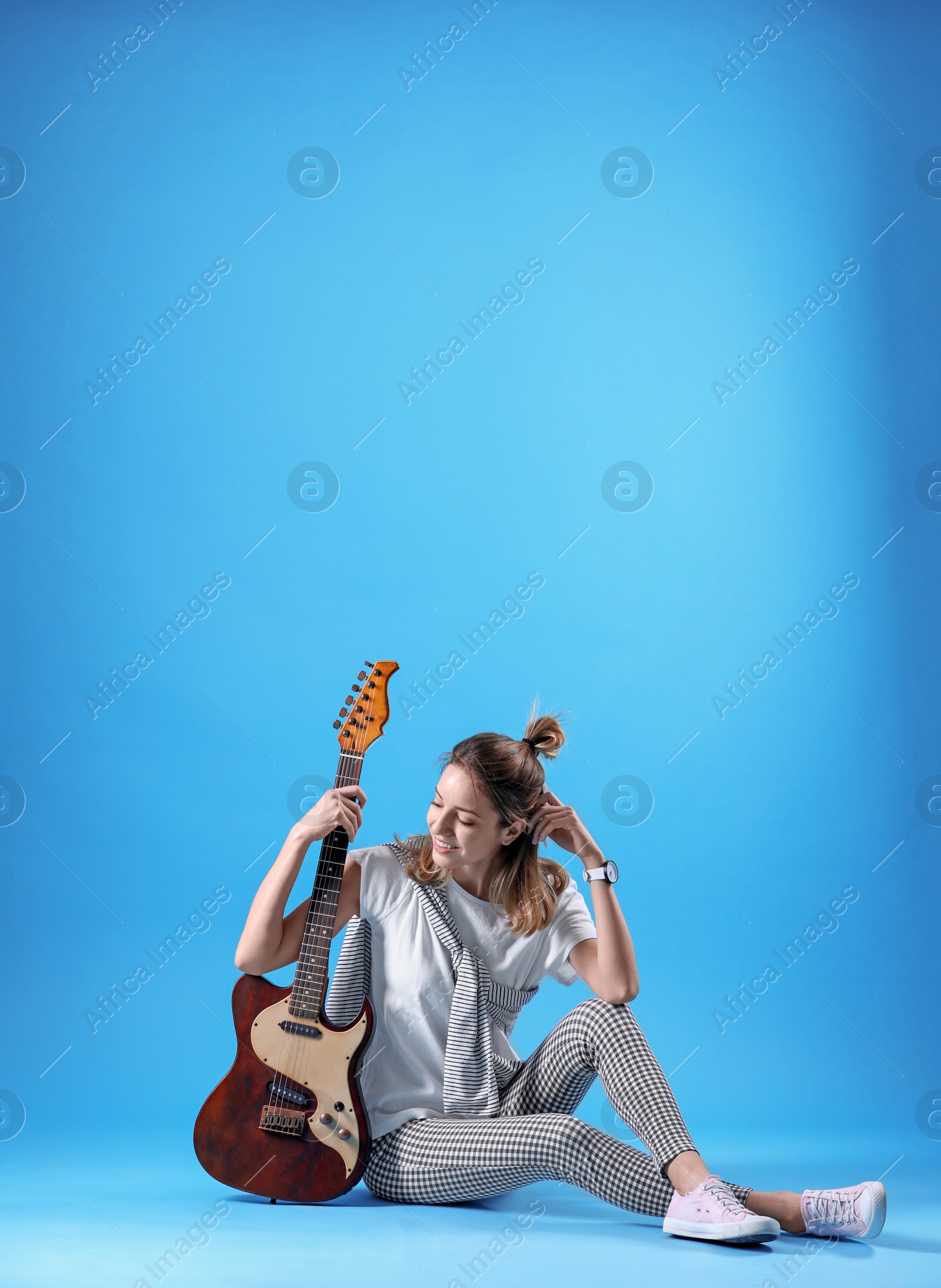 Photo of Young woman with electric guitar on color background