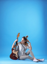 Photo of Young woman with electric guitar on color background