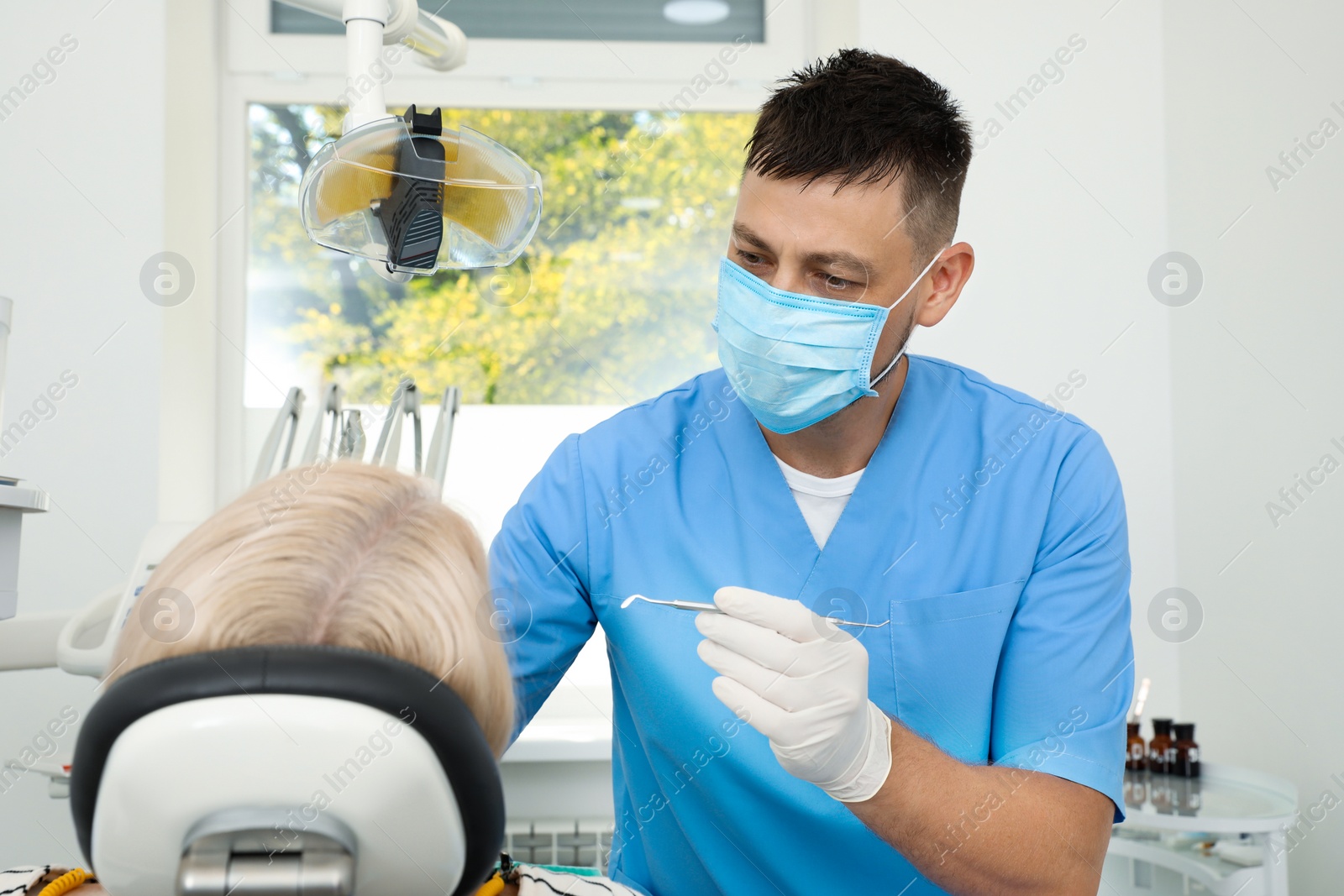 Photo of Professional dentist working with patient in clinic