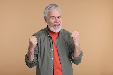 Photo of Portrait of surprised senior man on beige background