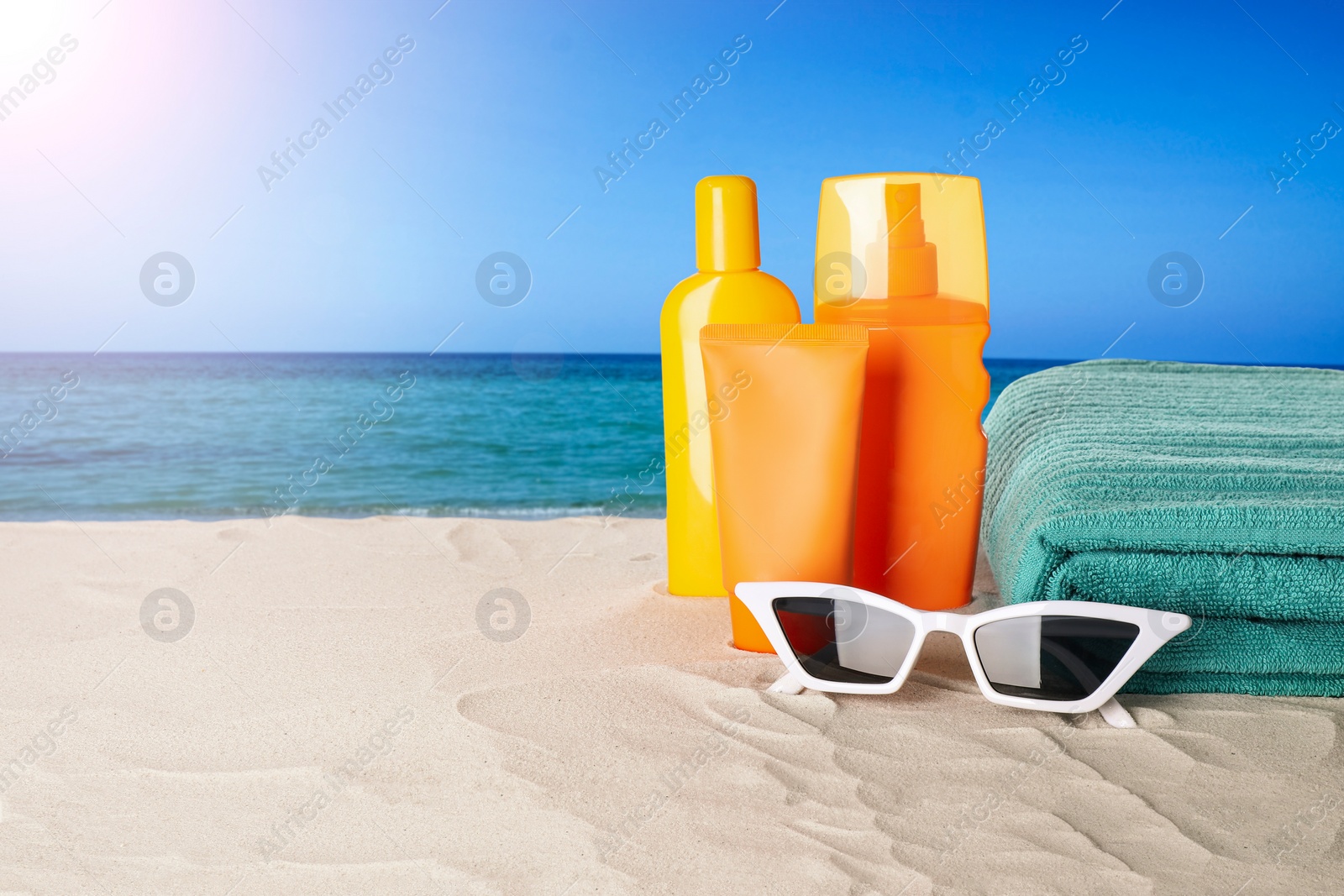 Image of Set of sun protection products and stylish accessories on sandy beach. Space for text