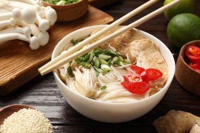 Photo of Delicious ramen with meat and ingredients on wooden table, closeup. Noodle soup