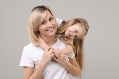 Family portrait of happy mother and daughter on grey background