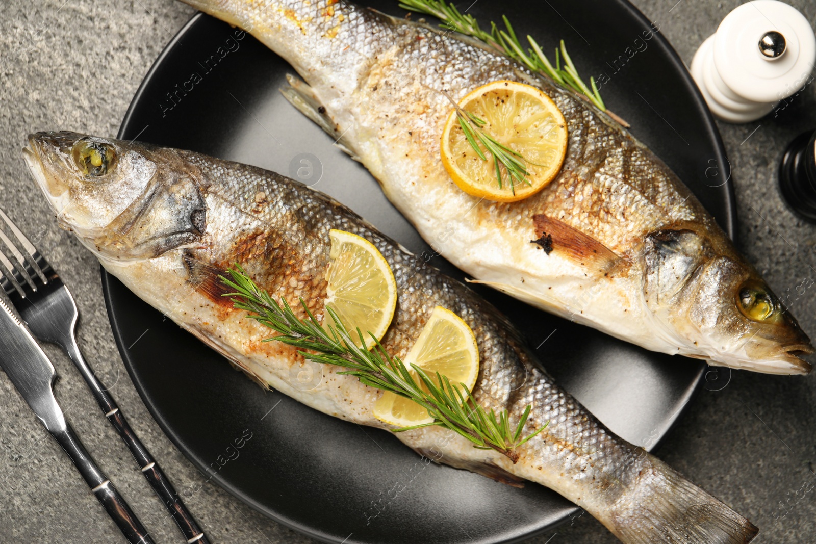 Photo of Delicious baked fish served on grey table, top view