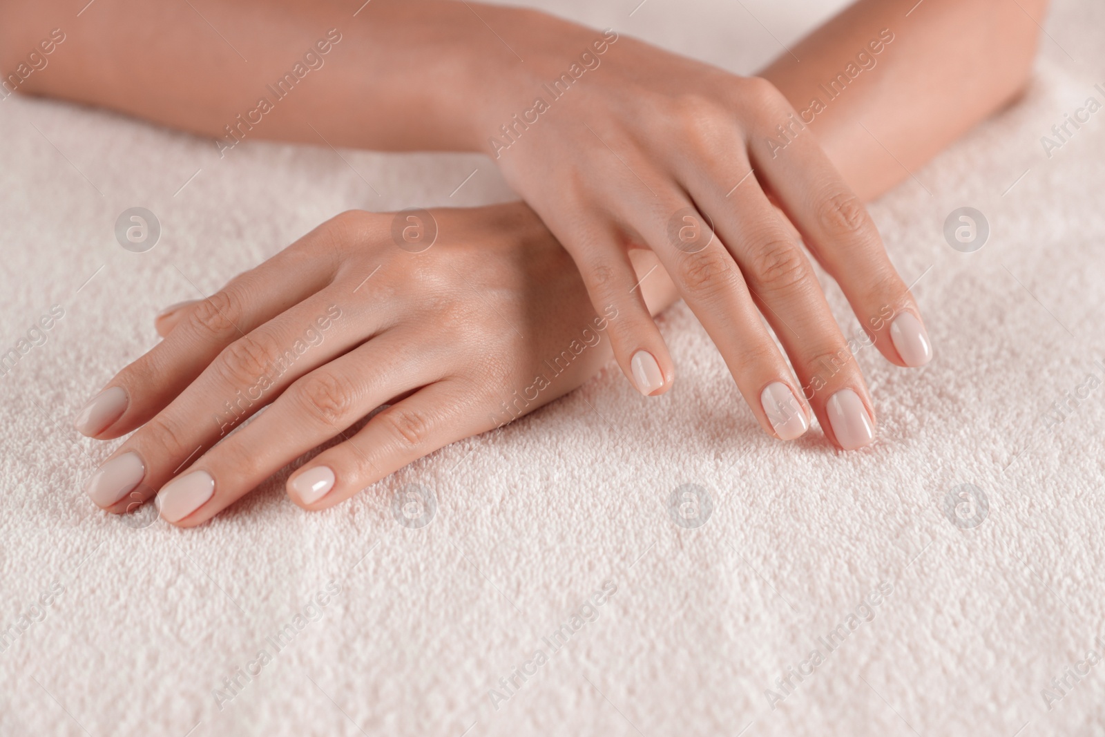 Photo of Woman with smooth hands and manicure on towel, closeup. Spa treatment
