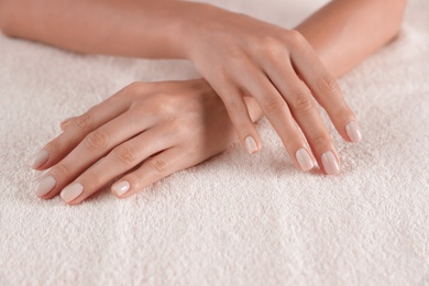 Photo of Woman with smooth hands and manicure on towel, closeup. Spa treatment