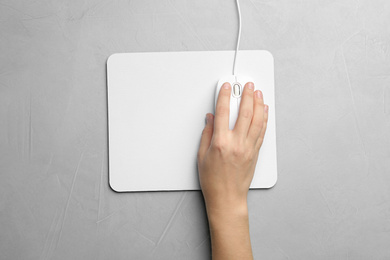 Photo of Woman using wired computer mouse on light grey table, top view. Space for text