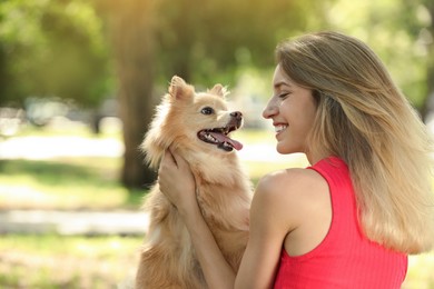 Young woman with her cute dog in park, space for text
