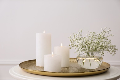 Photo of Vase with beautiful flowers and burning candles on table indoors. Interior elements